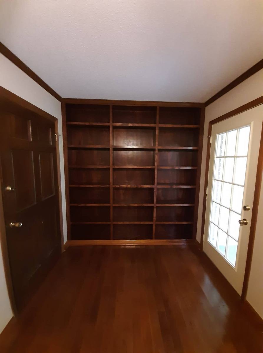 Completed custom stained wall shelving with wood trim in a finished room.
