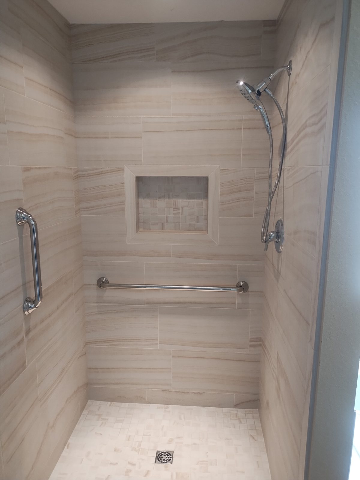 Custom tiled shower with built-in bench and niche by MMAC Renovation