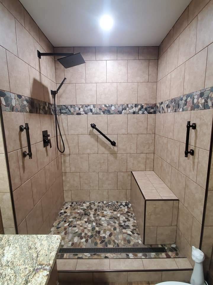 Accessible walk-in tile shower with bench, grab bars and pebble floor by MMAC Renovation