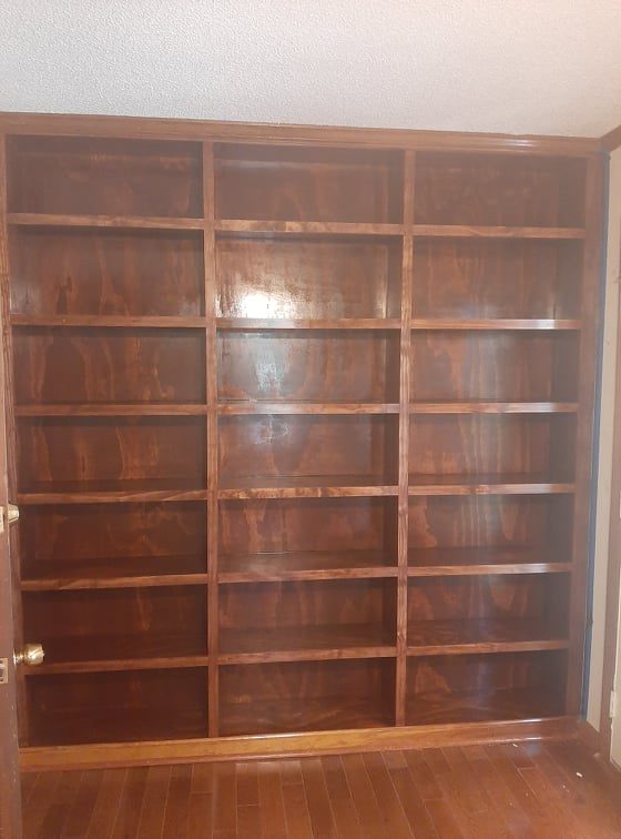Floor-to-ceiling stained wood built-in bookcase wall — custom carpentry, Laurens County GA