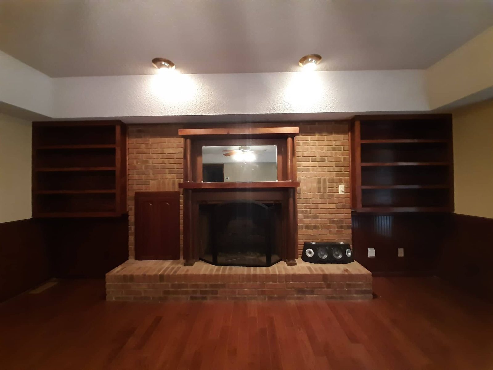 Brick fireplace with built-in shelving and hardwood floors — interior finish work
