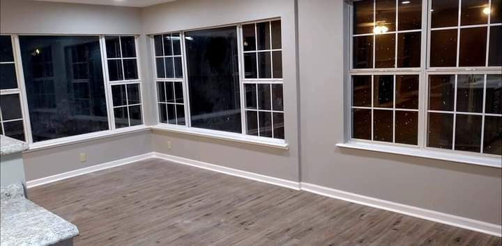 Sunroom with bay windows and plank flooring finished by MMAC Renovation