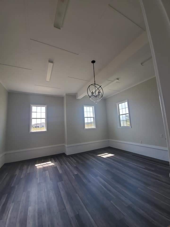 Vaulted room with chandelier, fresh paint and dark plank flooring