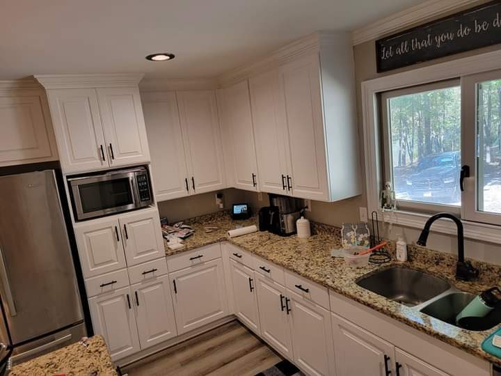 White kitchen with granite counters, undermount sink and window — finished by MMAC Renovation