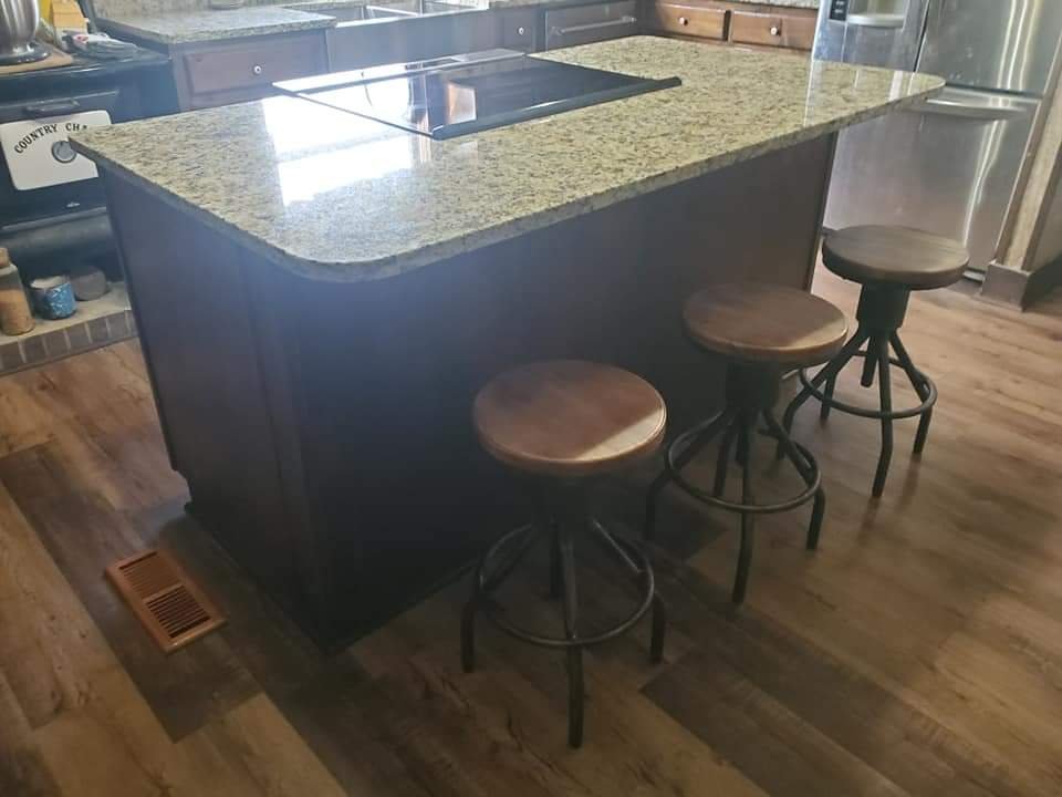 Kitchen island with granite top and bar seating by MMAC Renovation